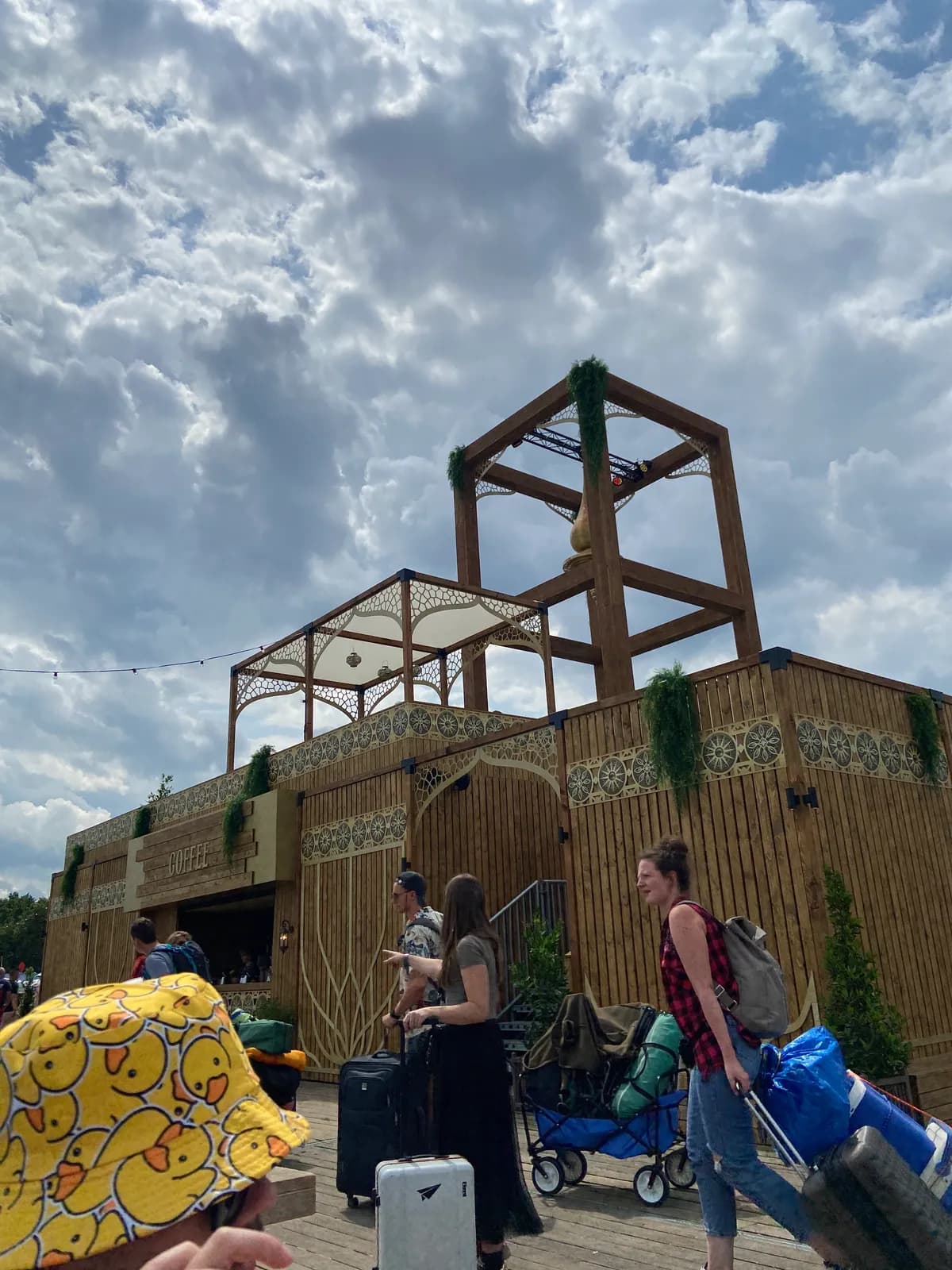 Festival-goers arriving at Dreamville with suitcases and carts in front of the Marketplace coffee stand